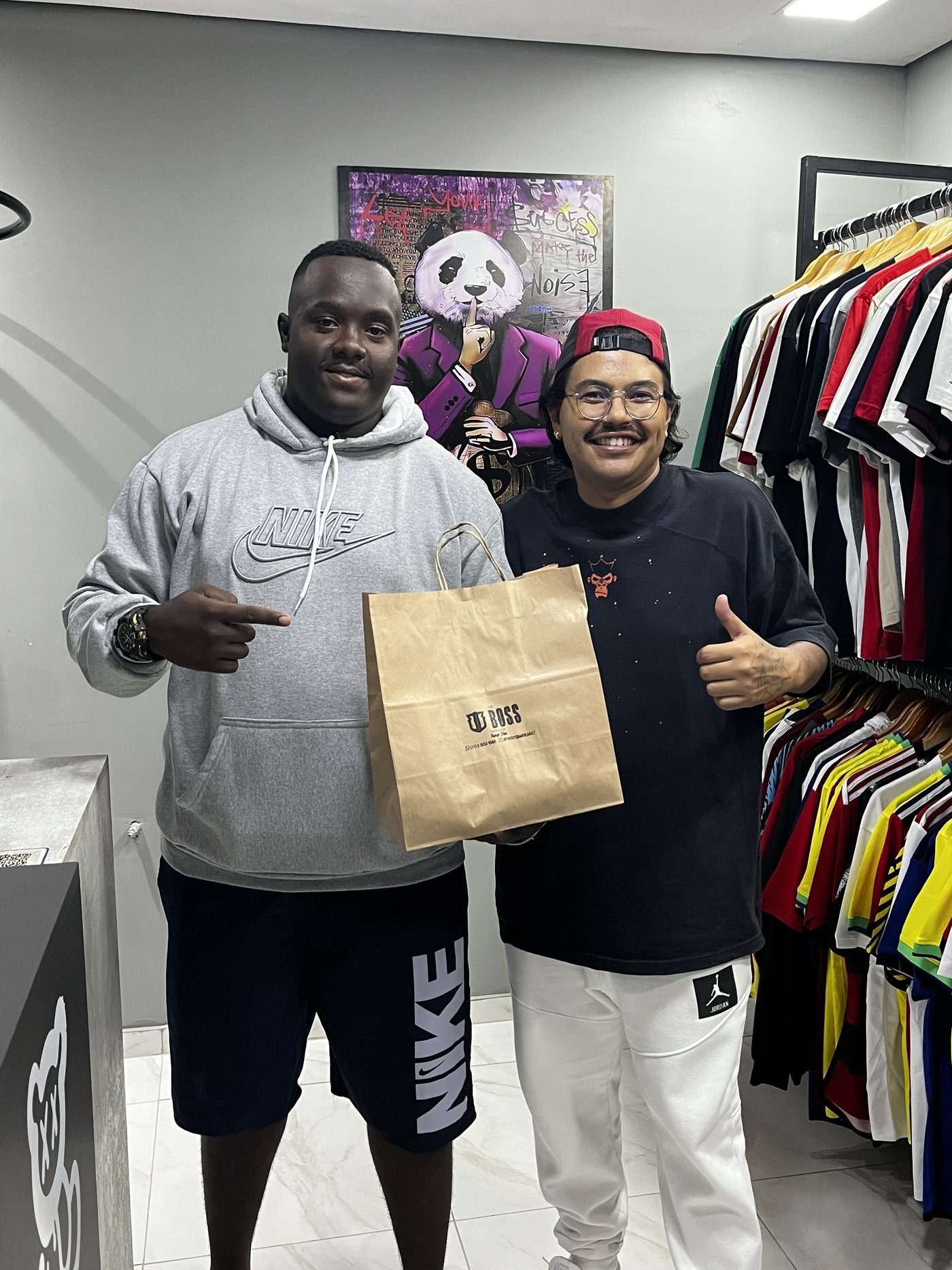 Interior da loja The Boss Concept com araras de roupas e clientes