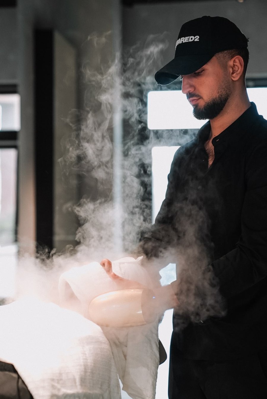 Barbeiro finalizando barba com toalha quente e vapor